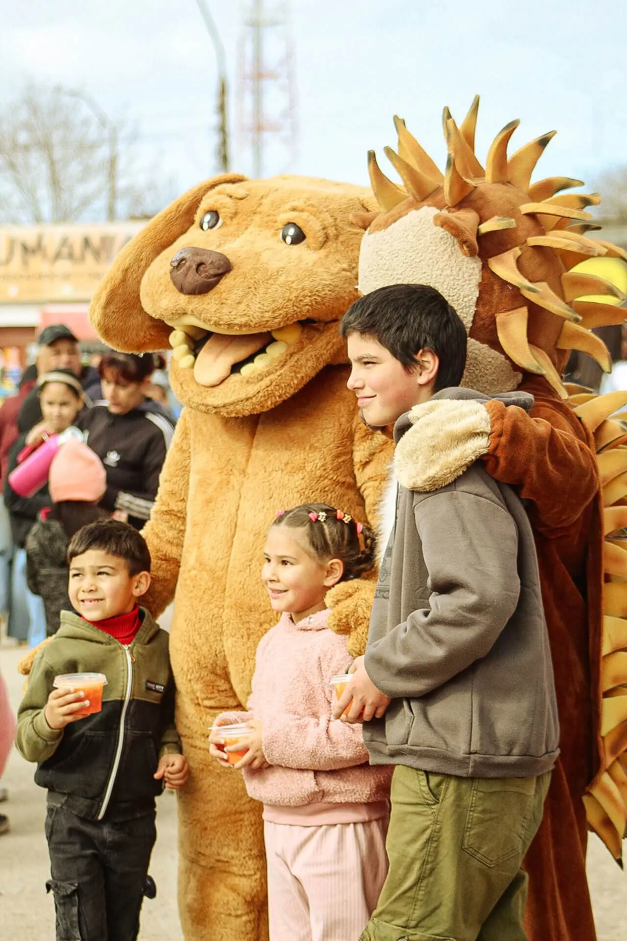 Tres niños posan abrazados a dos personajes disfrazados de animales.