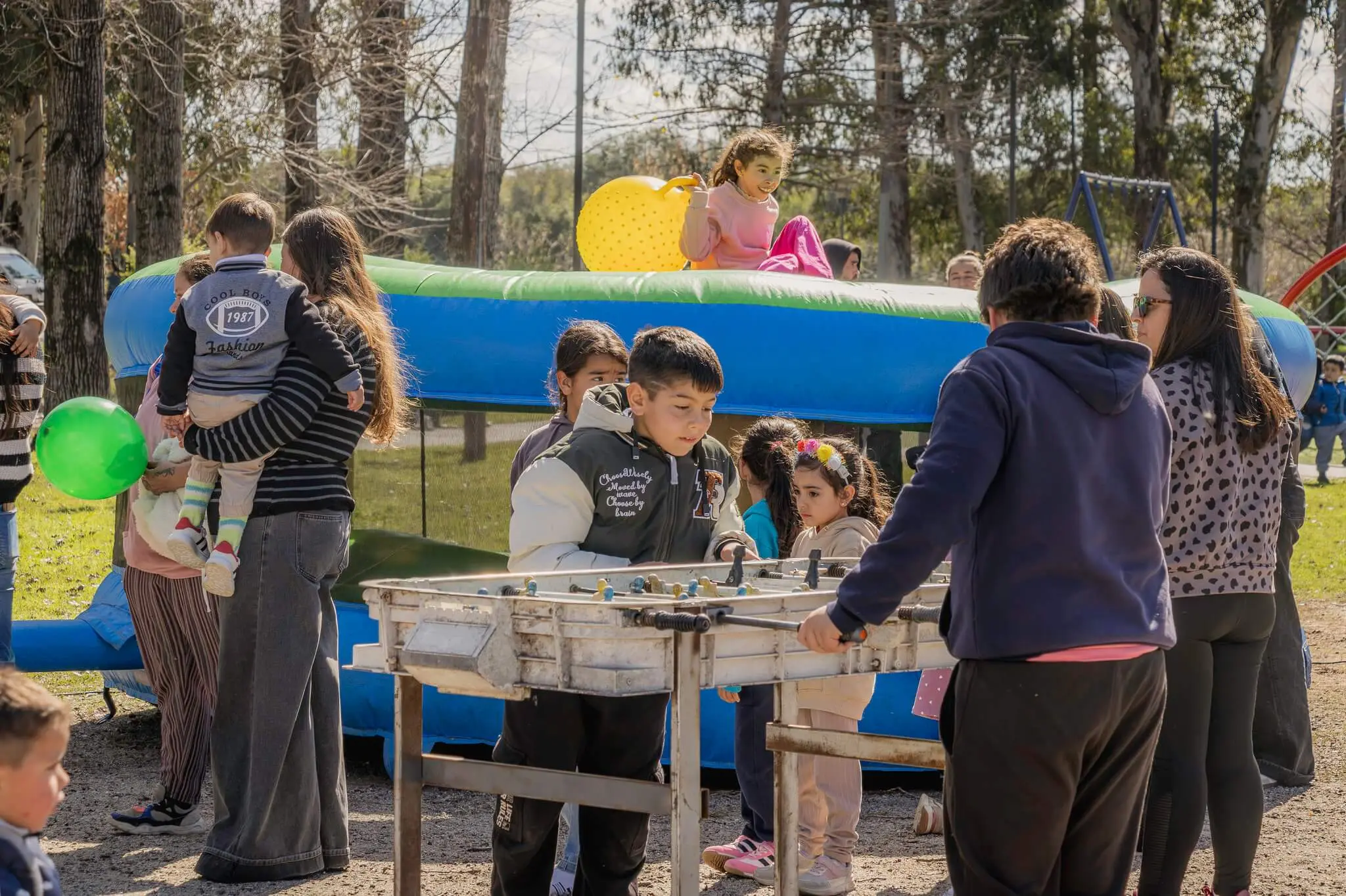 Niños juegan en un inflable en el Parque de la Primavera mientras adultos los acompañan.