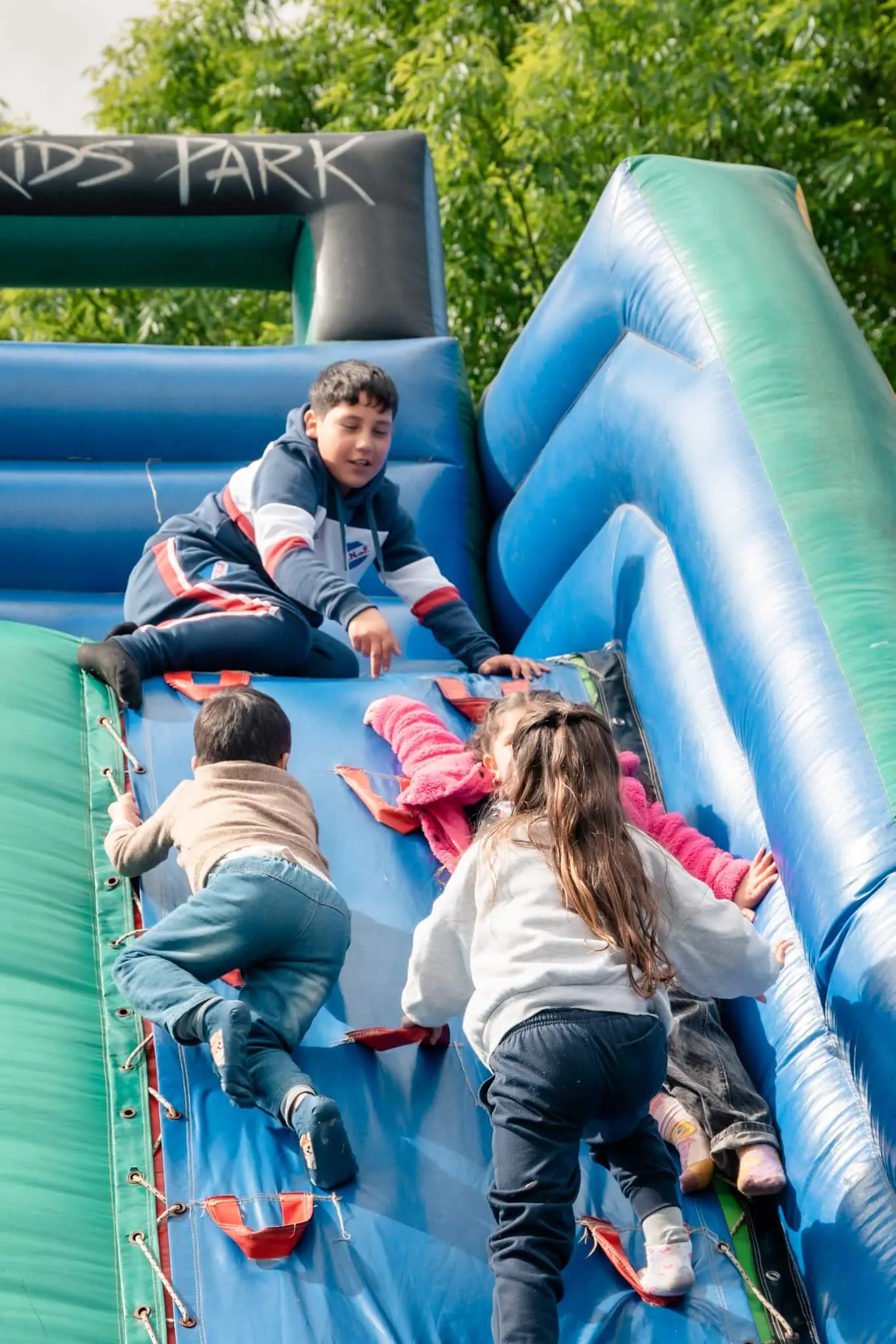 Niños trepan por un inflable azul y verde.