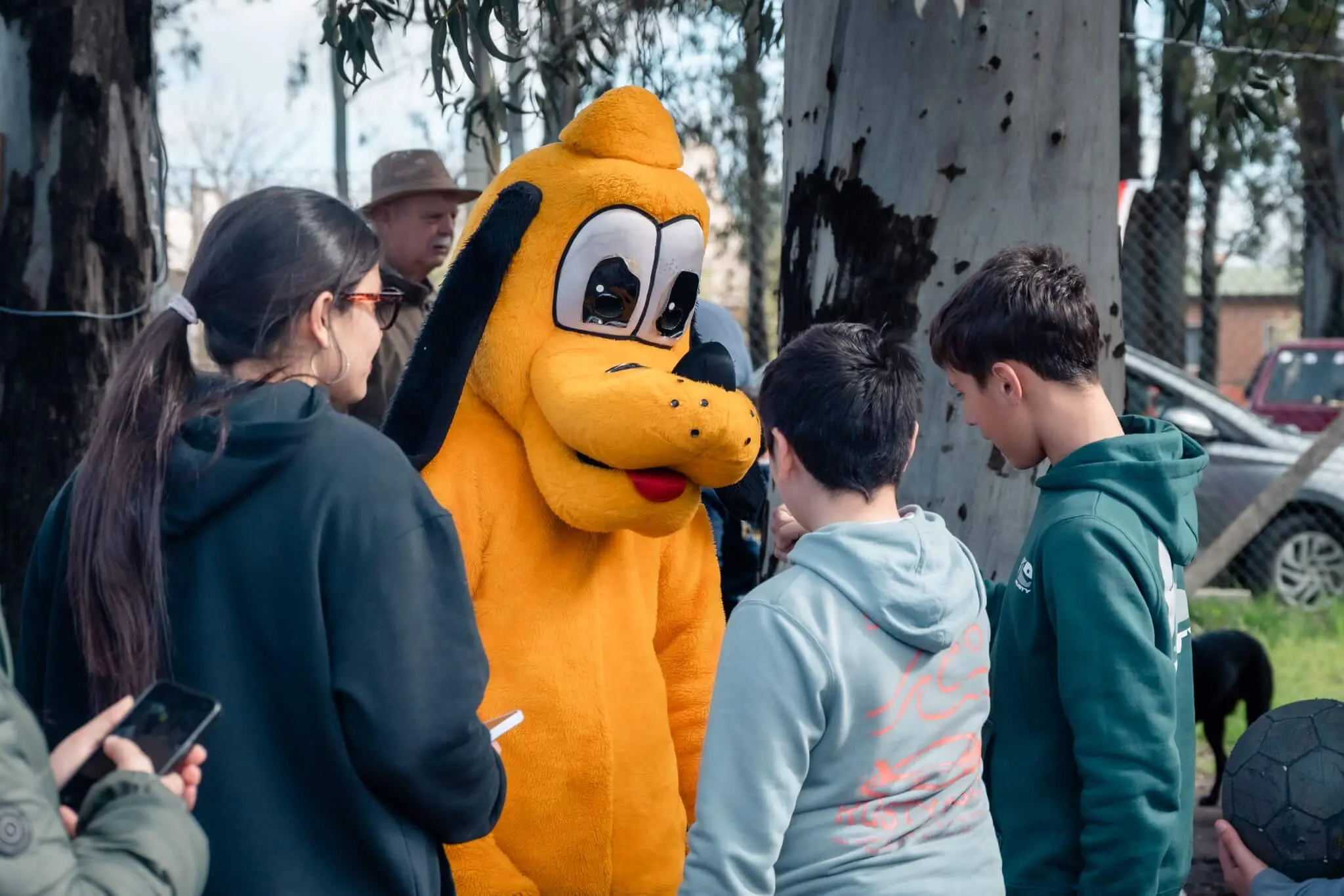 Adolescentes se sacan una foto con una persona disfrazada de Pluto.