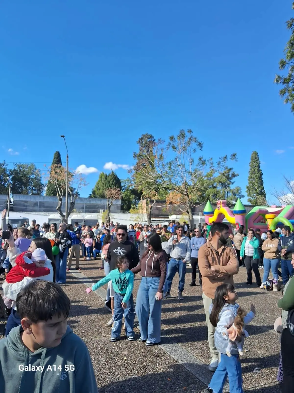 Plaza Rivera colmada de familias bajo un cielo azul, con inflables al fondo.