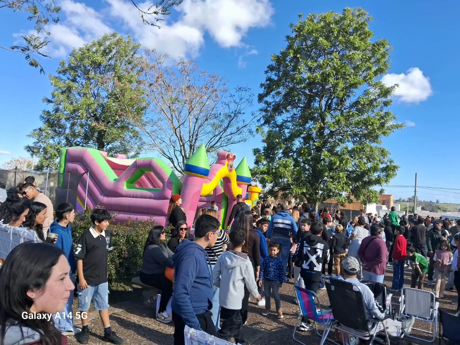 Multitud de niños y familias alrededor de un inflable de colores en la plaza.
