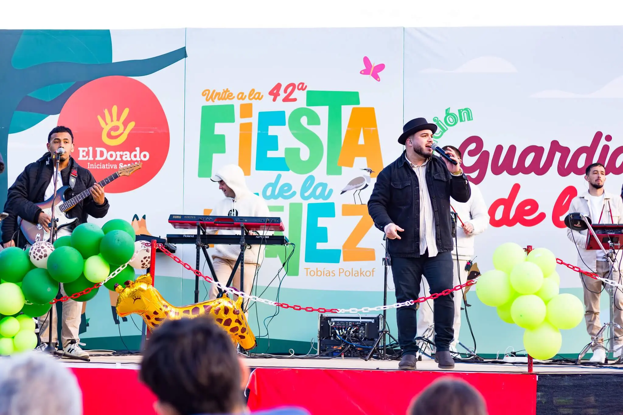 Músicos en el escenario de la 42ª Fiesta de la Niñez, con el cartel «Guardianes de la fauna».