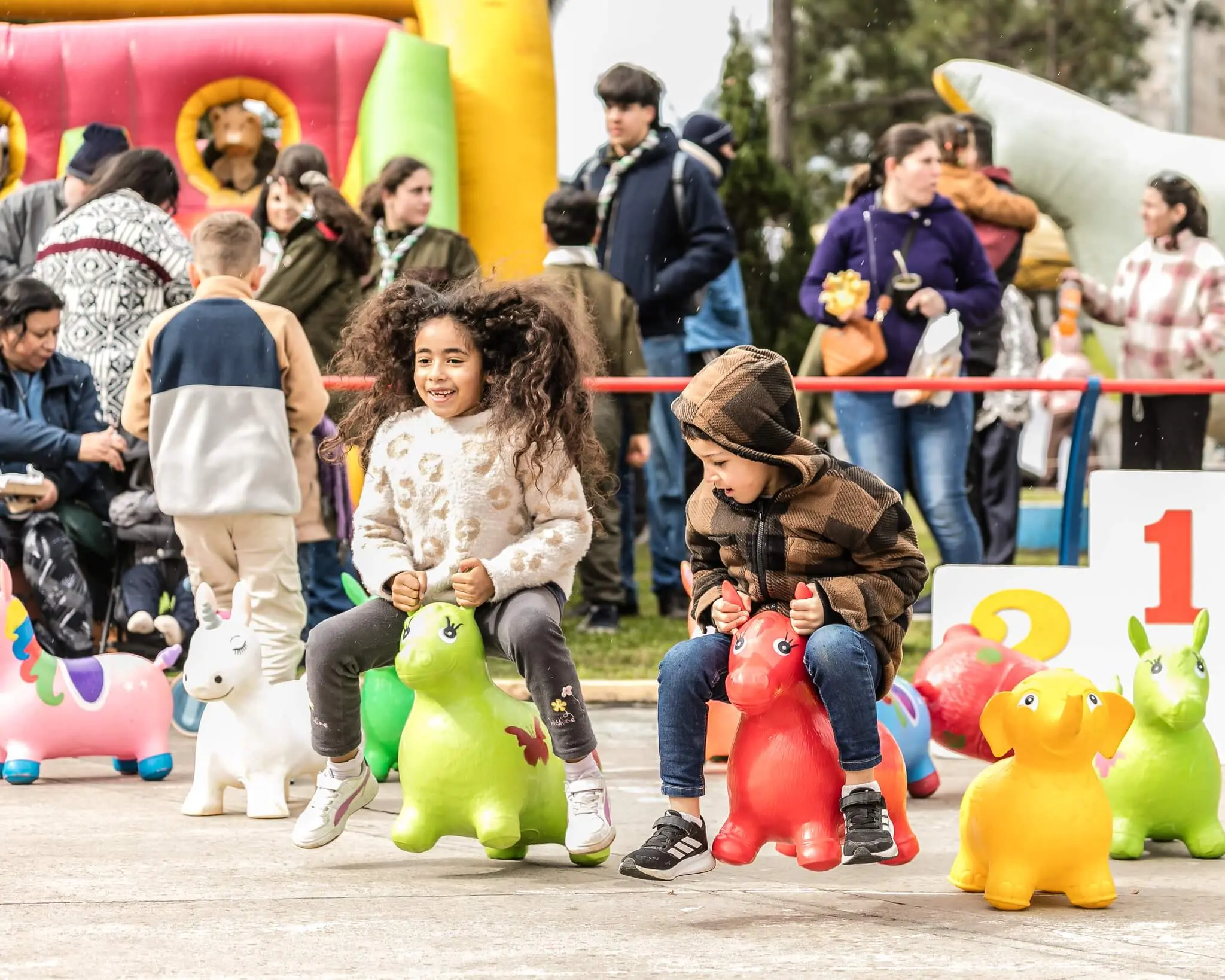Niños saltan sobre animales inflables de colores en una carrera.