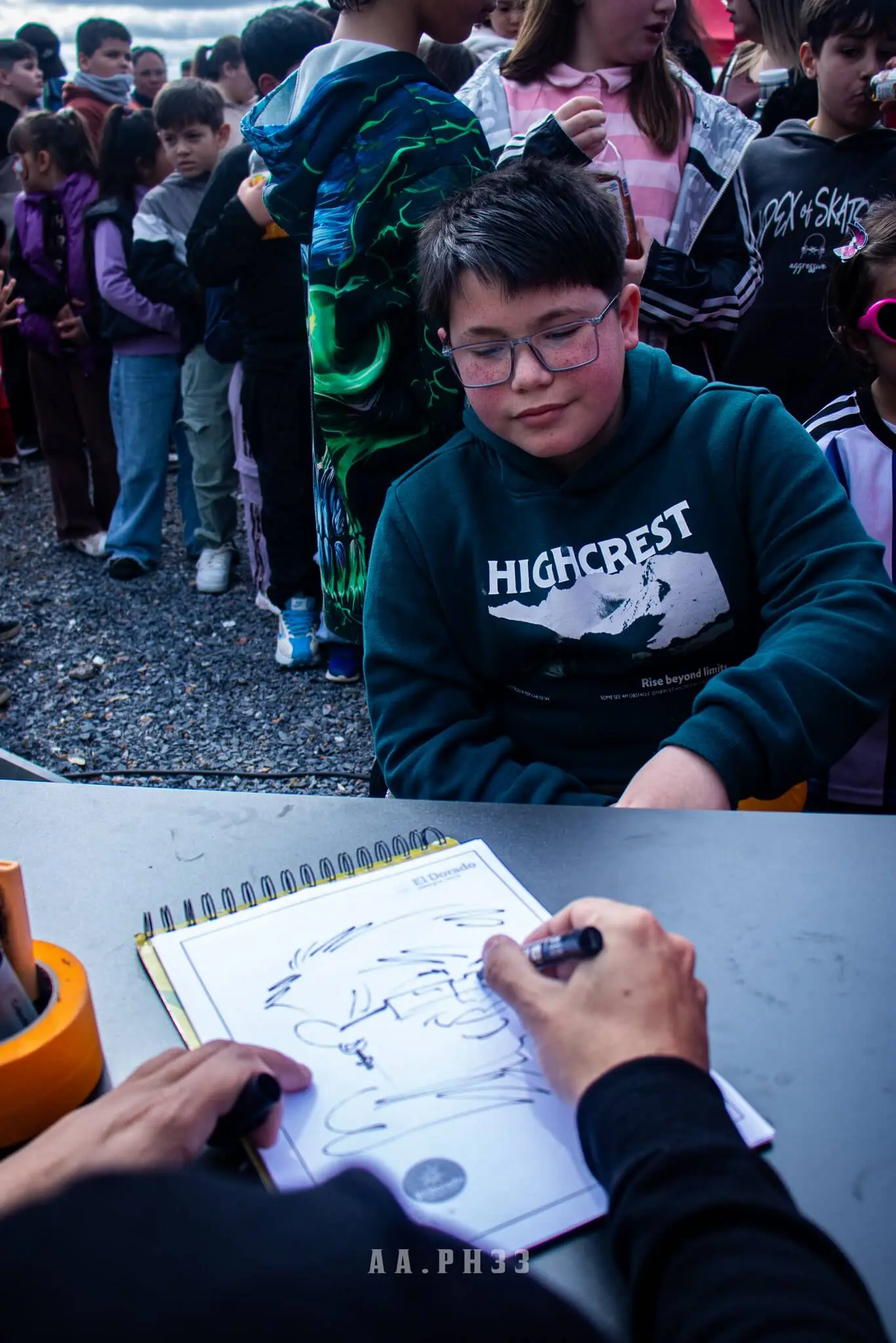Un niño espera mientras un dibujante le hace una caricatura en un cuaderno.