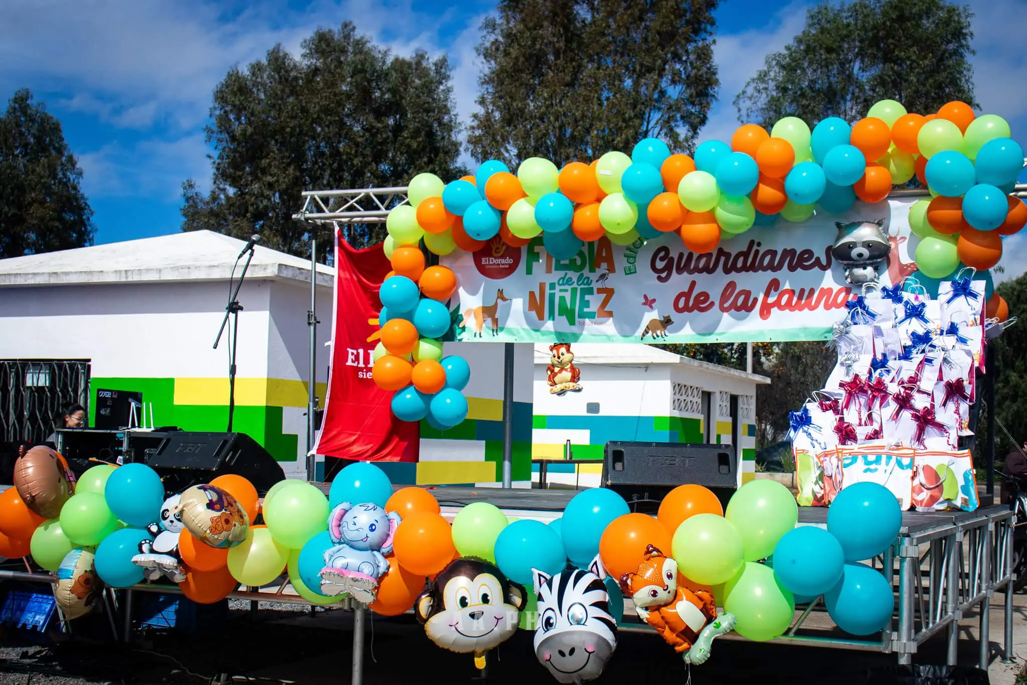 Escenario de la Fiesta de la Niñez decorado con arcos de globos de colores y animales inflables.