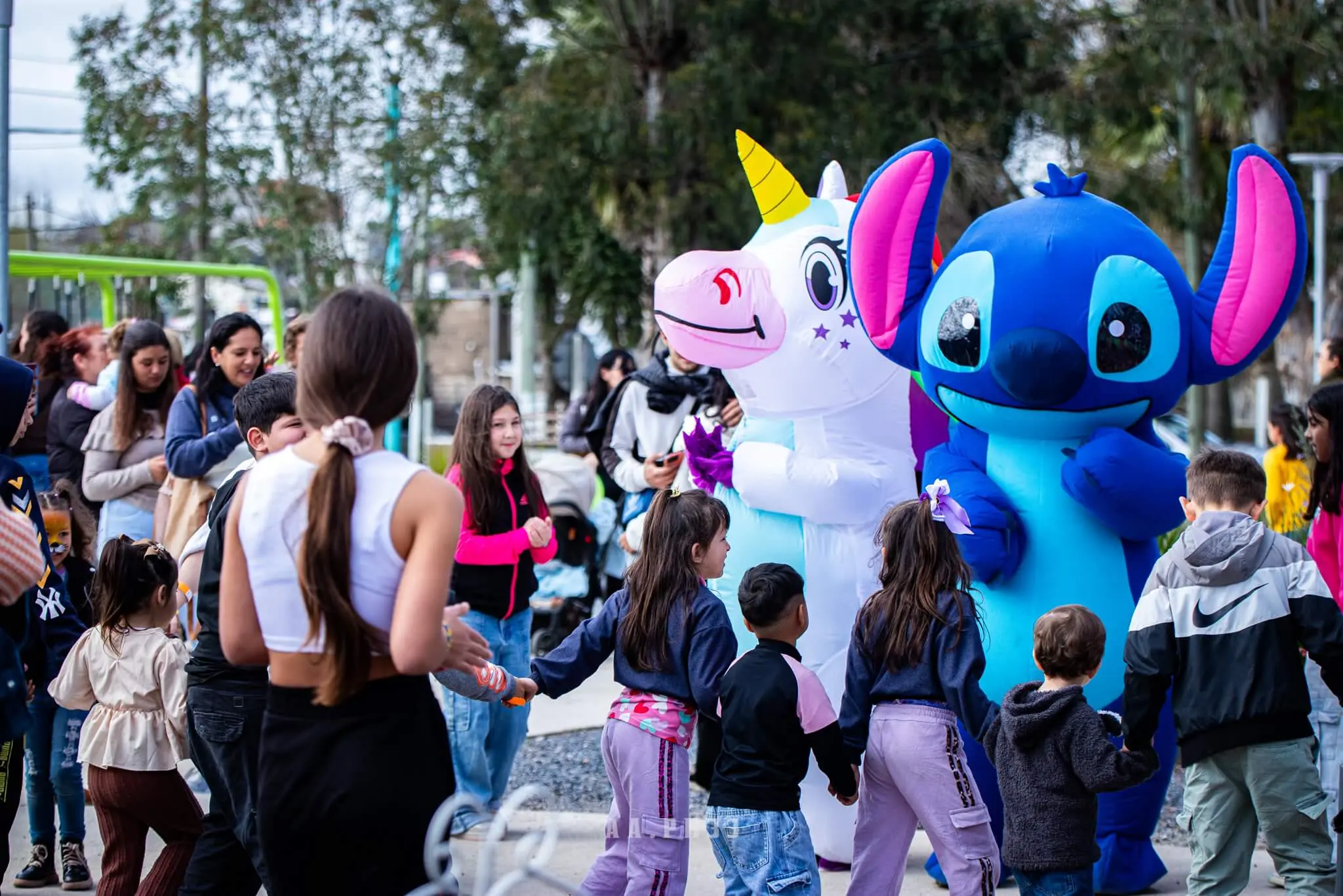 Niños y familias rodean a dos muñecos inflables, un unicornio y Stitch.